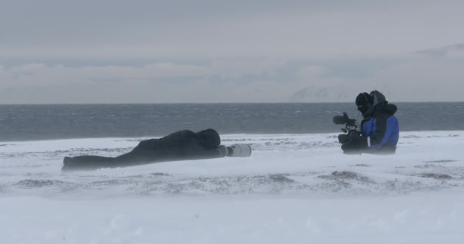 Two photographers sit in the snow
