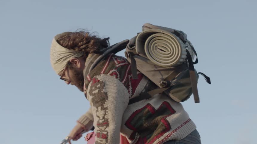 Man with backpack climbing on top of a vehicle