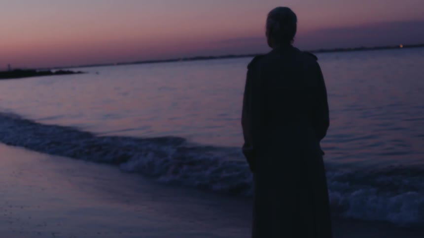 The tide moves over the womans feet on the beach