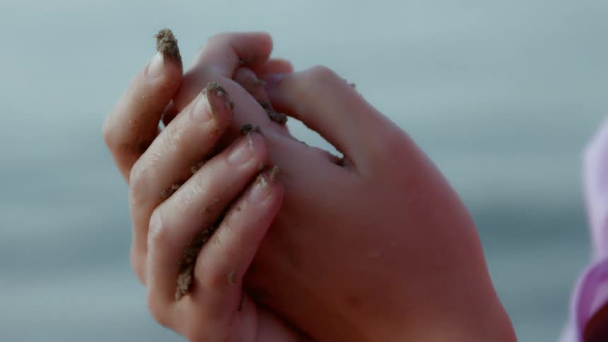 A woman rubs sand in her hands