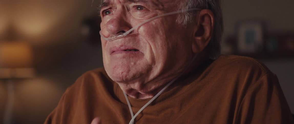 An elderly man with an oxygen tube appears emotional and in distress