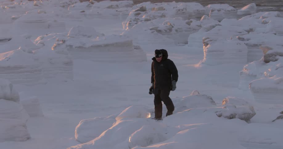 Man with camera walking in snow covered arctic wilderness