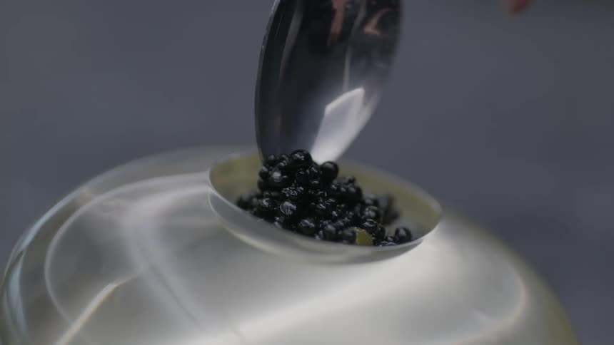 Spoon scooping black caviar from a dish