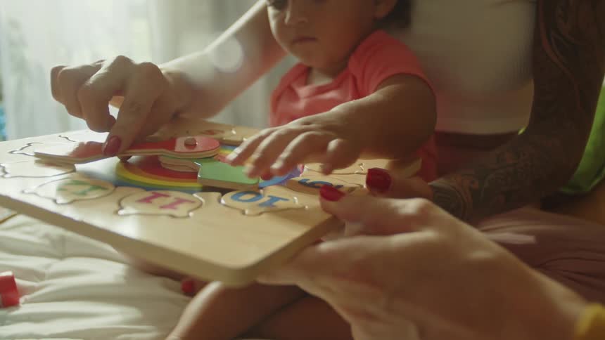 Little girl with two adults on a bed playing with a toy