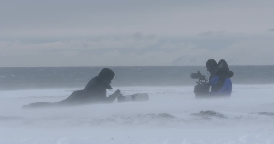 Two people are using camera equipment in a snowstorm