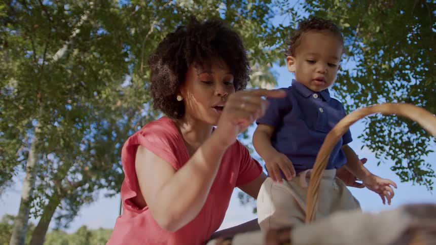A mother shows her son an apple at a picnic
