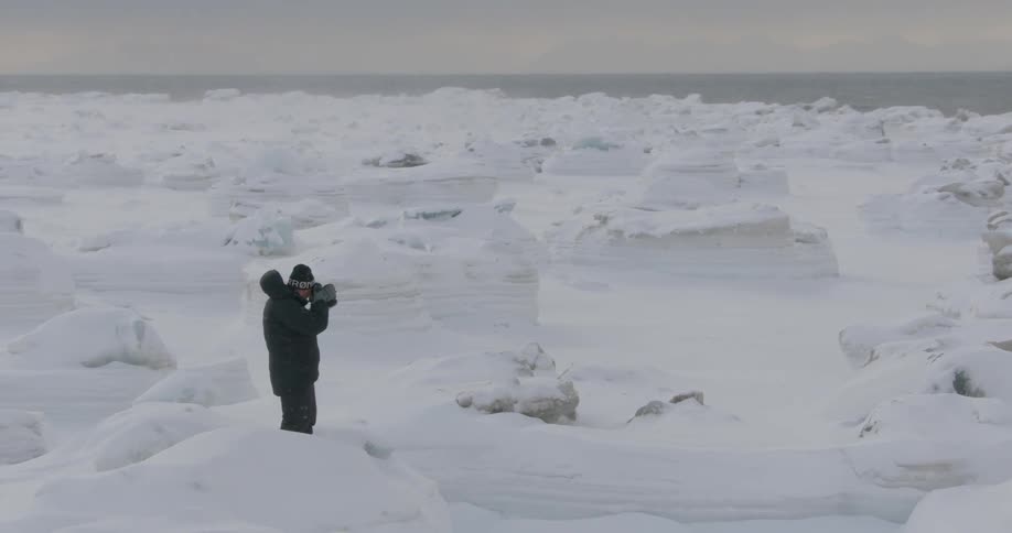 A photographer takes photos in a snowy and icy landscape