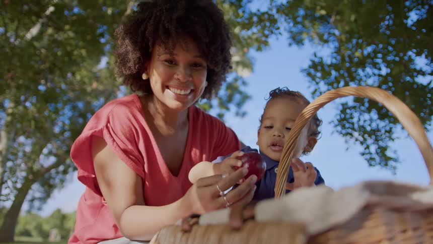 A mother hands her son an apple