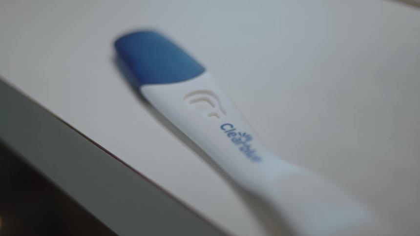 A woman picks up a home pregnancy test kit
