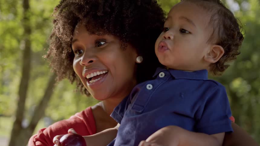 Mother hugging a small child in a treelined environment