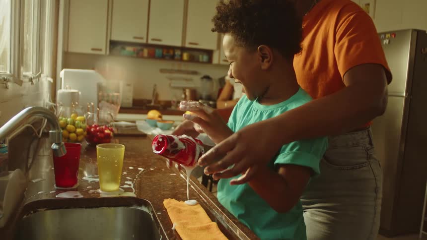 Mother lovingly helps her son with kitchen chores