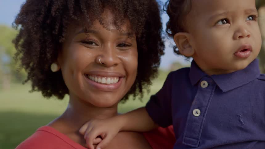 A mother smiles while holding her son