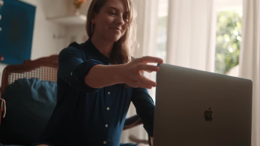 A pregnant woman is sitting comfortably and smiling during a video call
