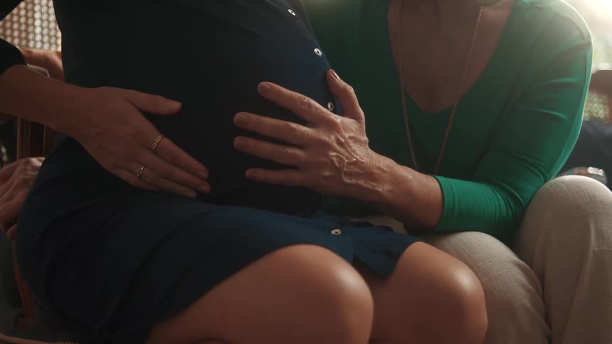 A pregnant woman is having her belly rubbed
