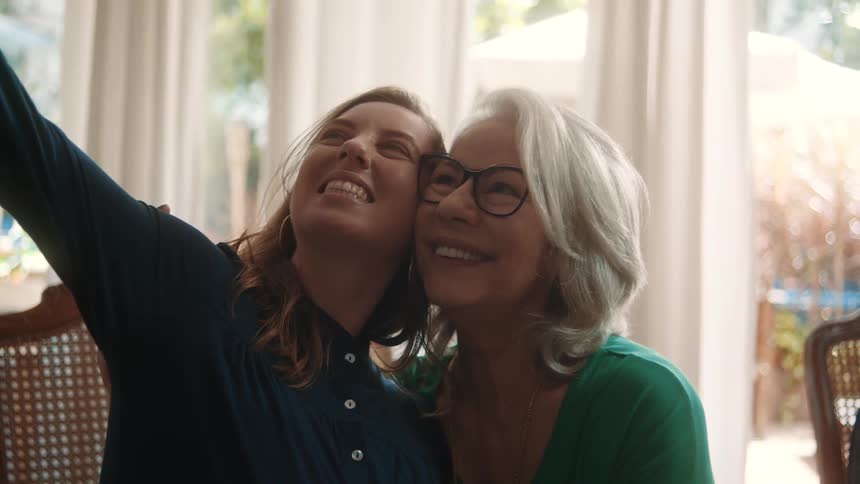 Two women happily take a selfie together indoors