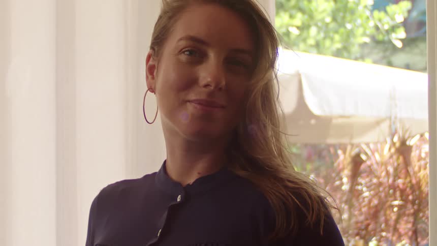 A pregnant woman standing by the window indoor at daytime moving her head to the sides