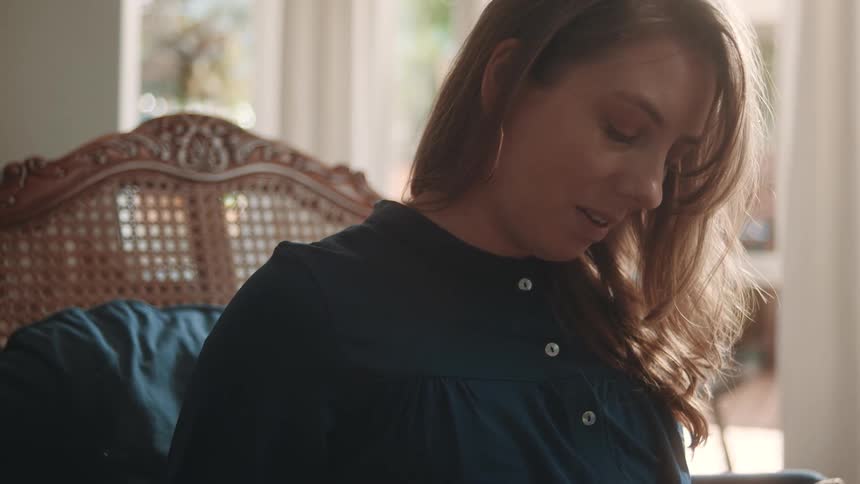 Pregnant woman sitting in an armchair with happy expression