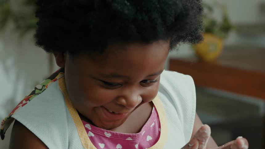 Face of a smiling black girl toddler at dawn with flours on her hand