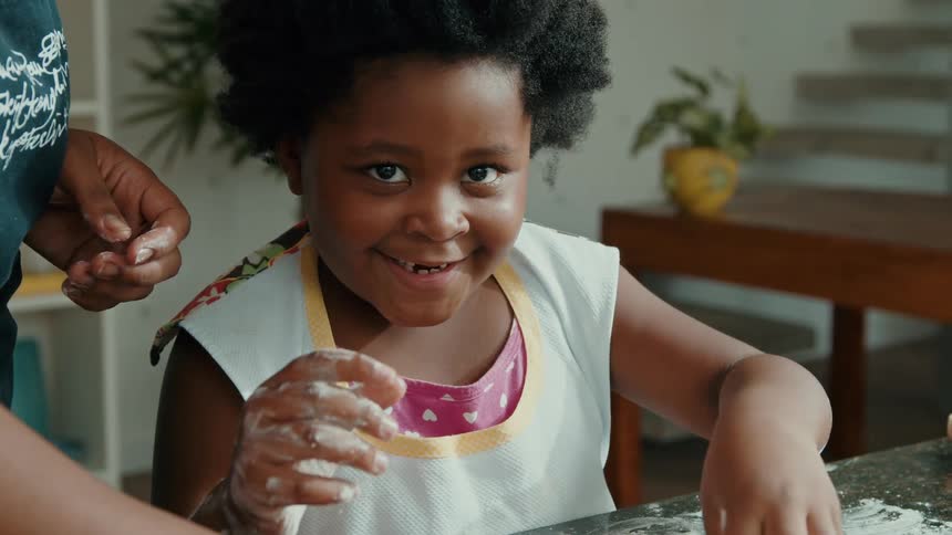 A girl and her mother mix flour and smile