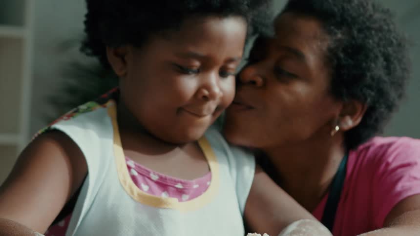 A mother kisses her daughter on the cheek