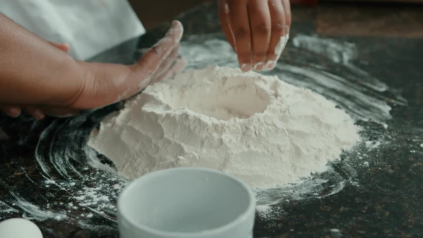 Two people pat the pile of flour