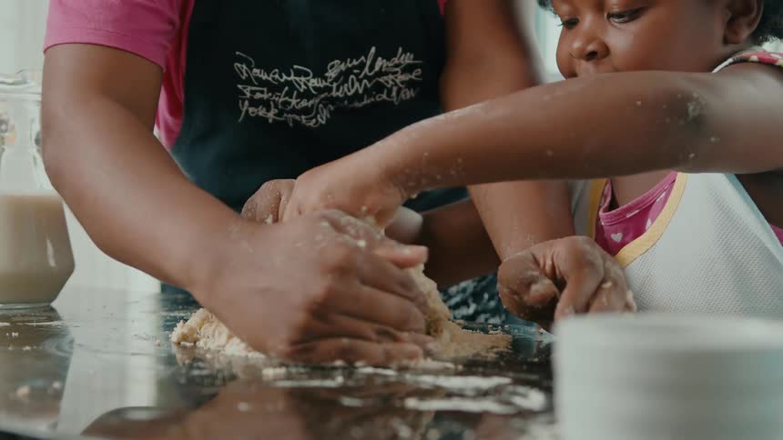 A mother and daughter are mixing flour on the counter
