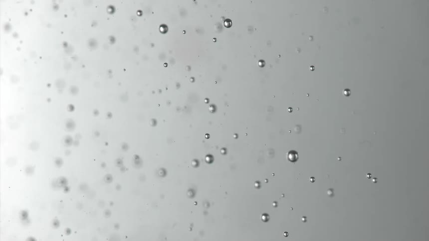 Multiple air bubbles of various sizes sink through a clear liquid against a light gray background