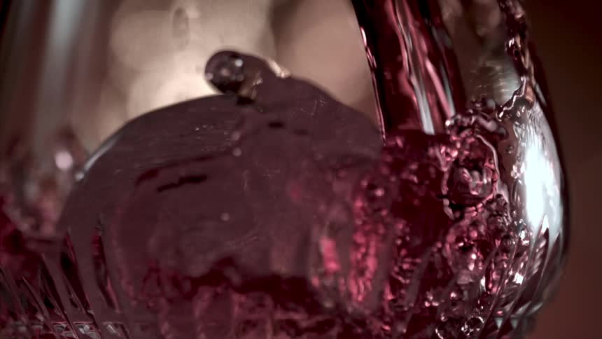 A red liquid being poured into a glass and splashing around