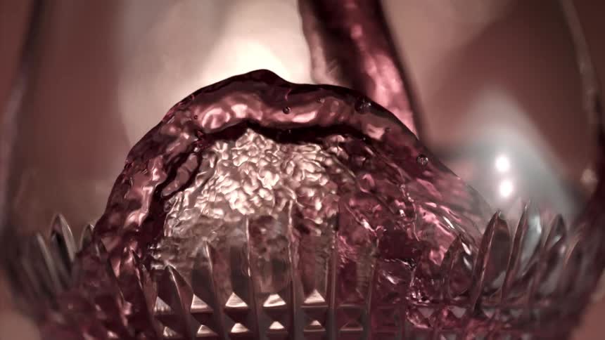 Close up of a glass cup being filled with a red drink