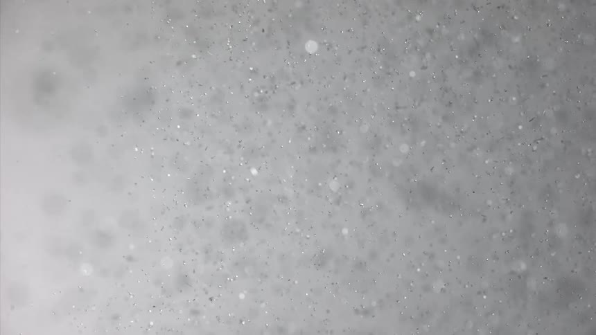 Water splashes midair forming a burst of tiny bubbles that glisten as they drift and disperse
