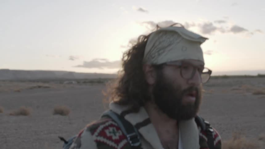 Man walks in the desert at sunset