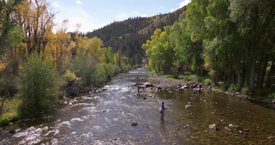 Aerial of three fishermen in a stream fly fishing in the wilderness