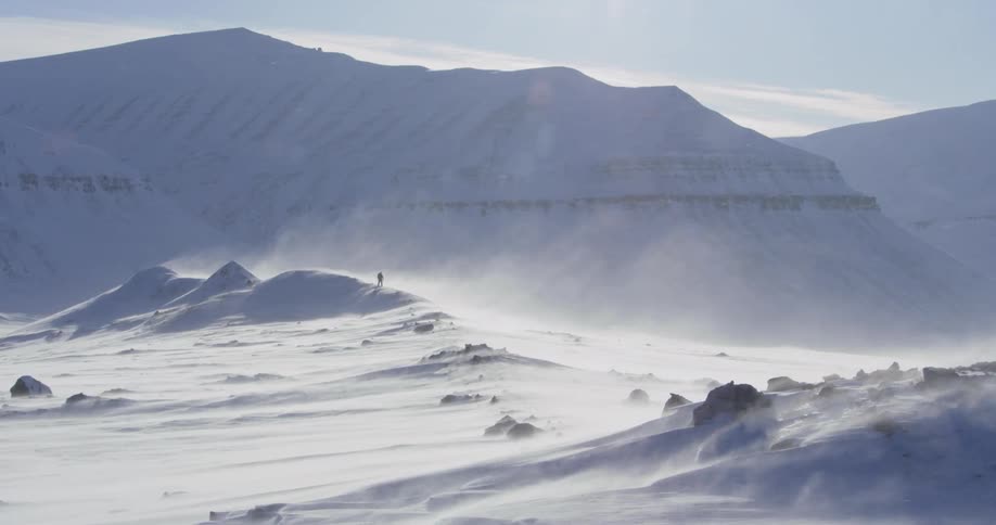 Snow blows across the air as a man treks through it