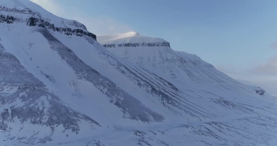 The tall mountain is covered with snow on a sunny day