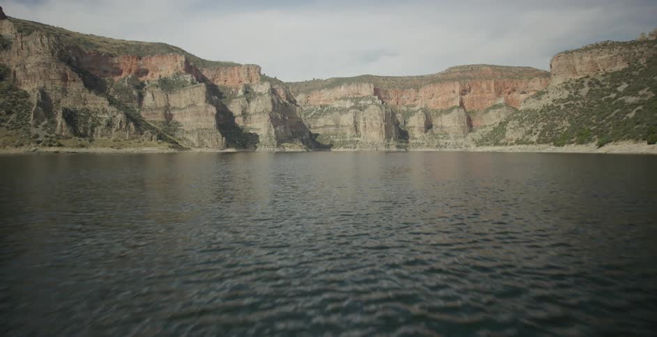 Steep canyon cliffs rise above a calm lake under a clear sky