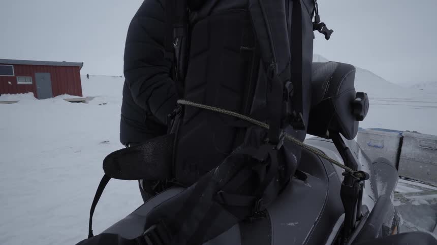 A man straps a bag to a snowmobile