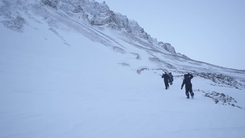 People walk on a mountainside in the snowy wilderness