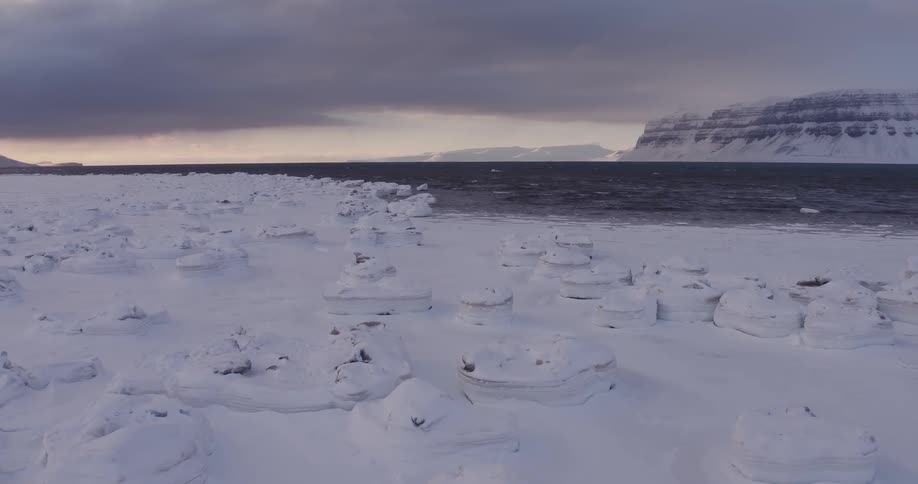 The shore is surrounded by rocks and snow