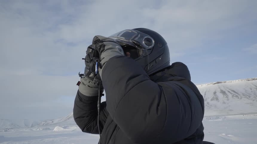 A man is looking over the horizon with binoculars