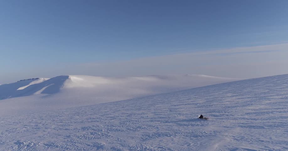 A snowmobile races on a clear day