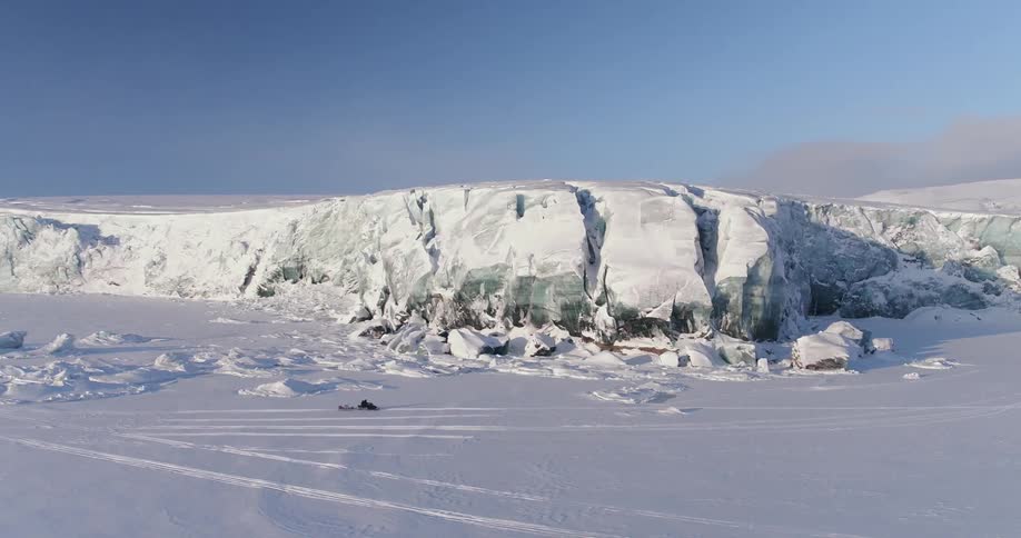 A snowmobile races along an ice mountain