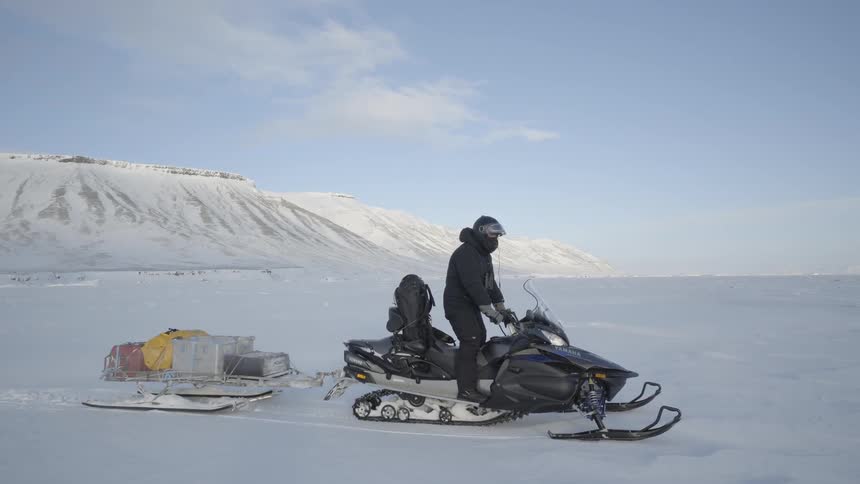 Man pulling cargo behind a snowmobile in the arctic