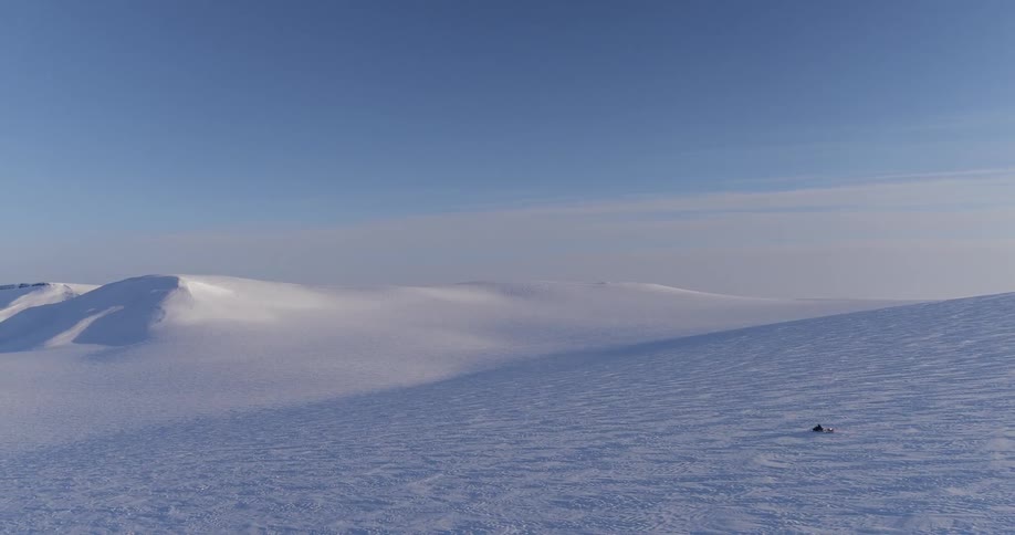 A snowmobile races down a steep snowy hill