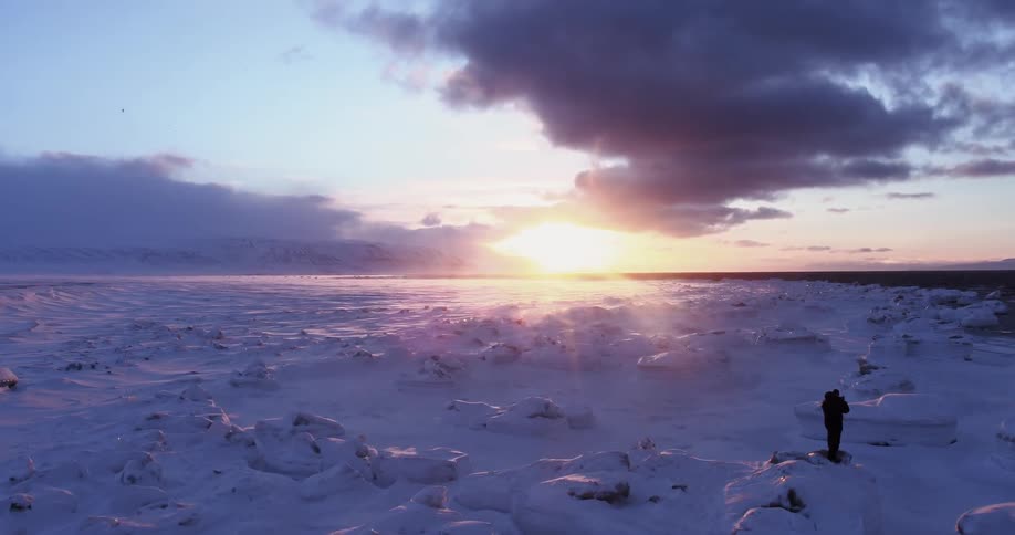 A man walks on a bumpy snow field