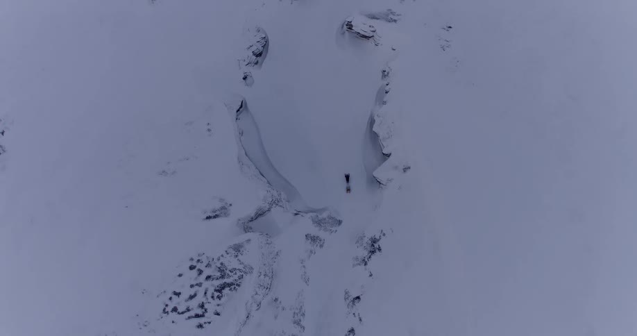 A snowmobile cuts between two snowy hills