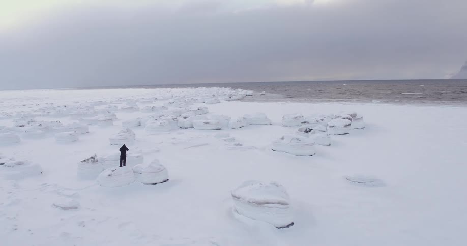 A man is standing on a rock by the shore
