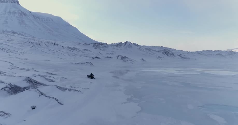 A snowmobile races from the snow covered mountain
