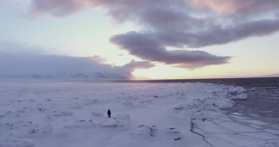 A photographer snaps a photo in the frigid wilderness at sunset