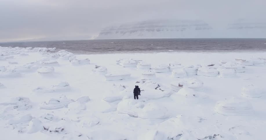 Man with camera walking in snow covered arctic wilderness