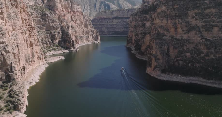 Small boat traveling through a sea surrounded by mountains